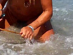 Wanita matang dengan tindik puting yang terbuka lebar dan tindik berbilang pada puki di pantai